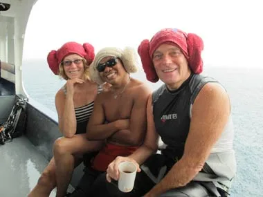 Three divers on a boat deck wearing towel hats