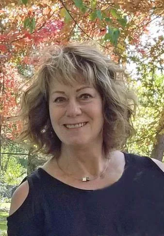 Portrait of Vivian Weber smiling, with autumn leaves behind her